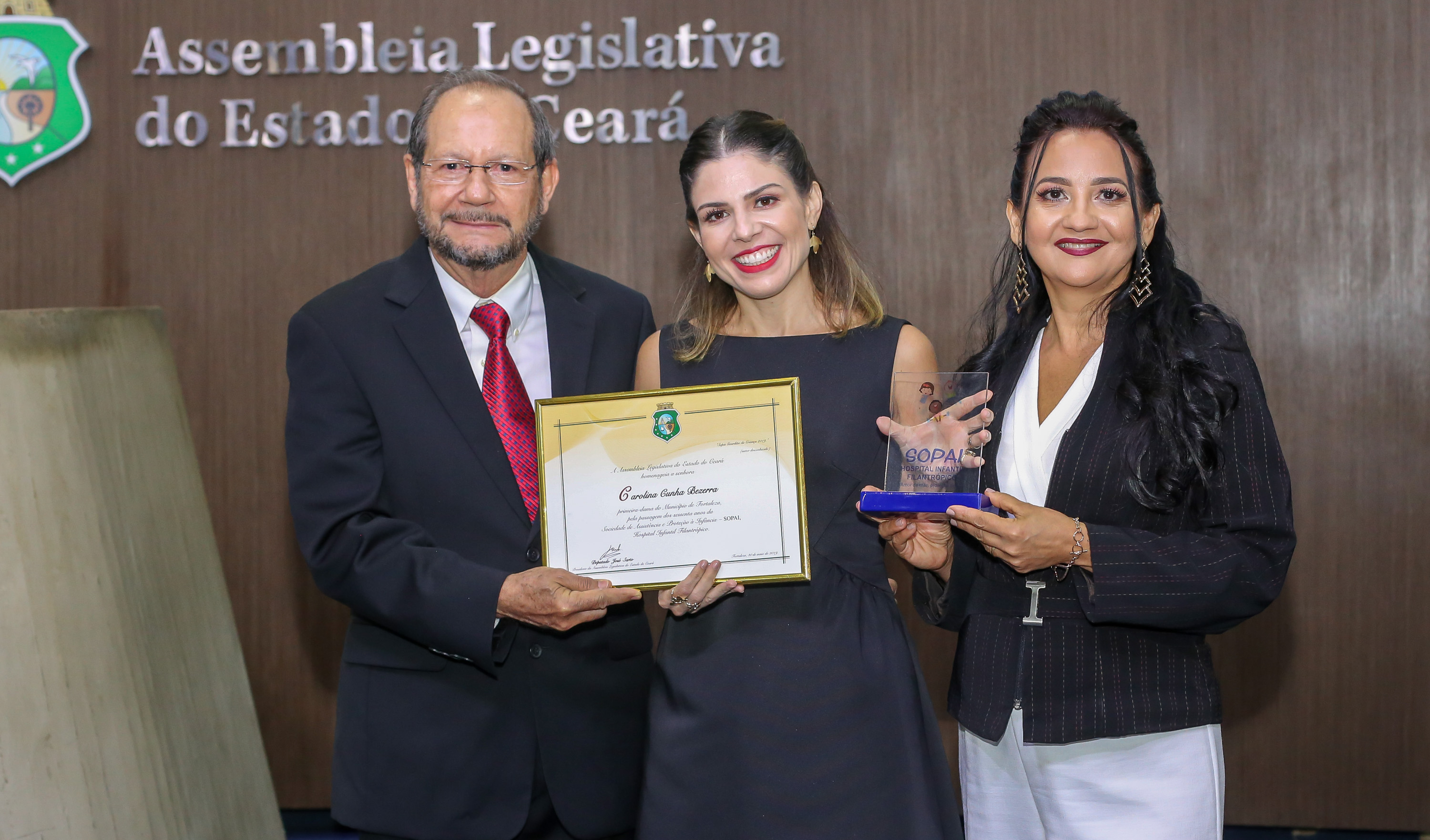 três pessoas posam para a foto